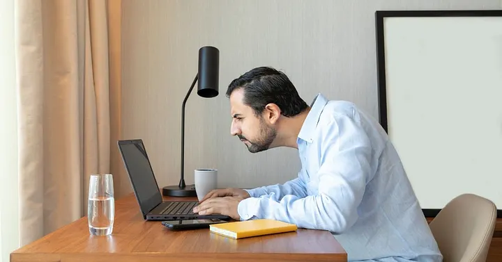 A guy on a bent position squinting hard at a screen