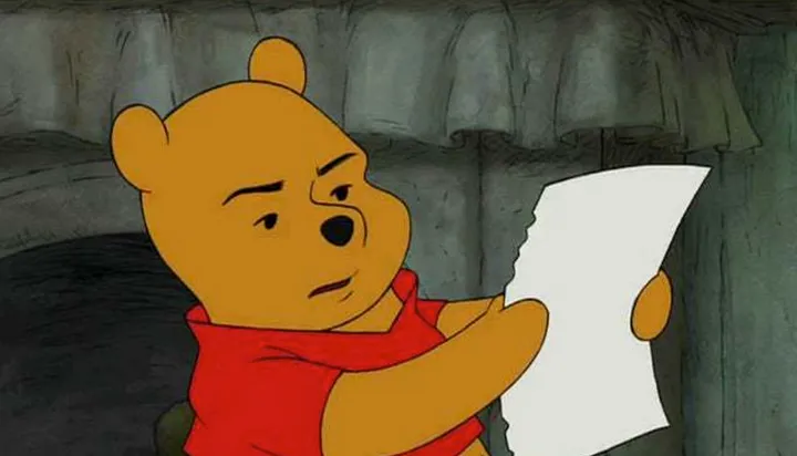Winnie the Pooh seriously looking into a piece of paper