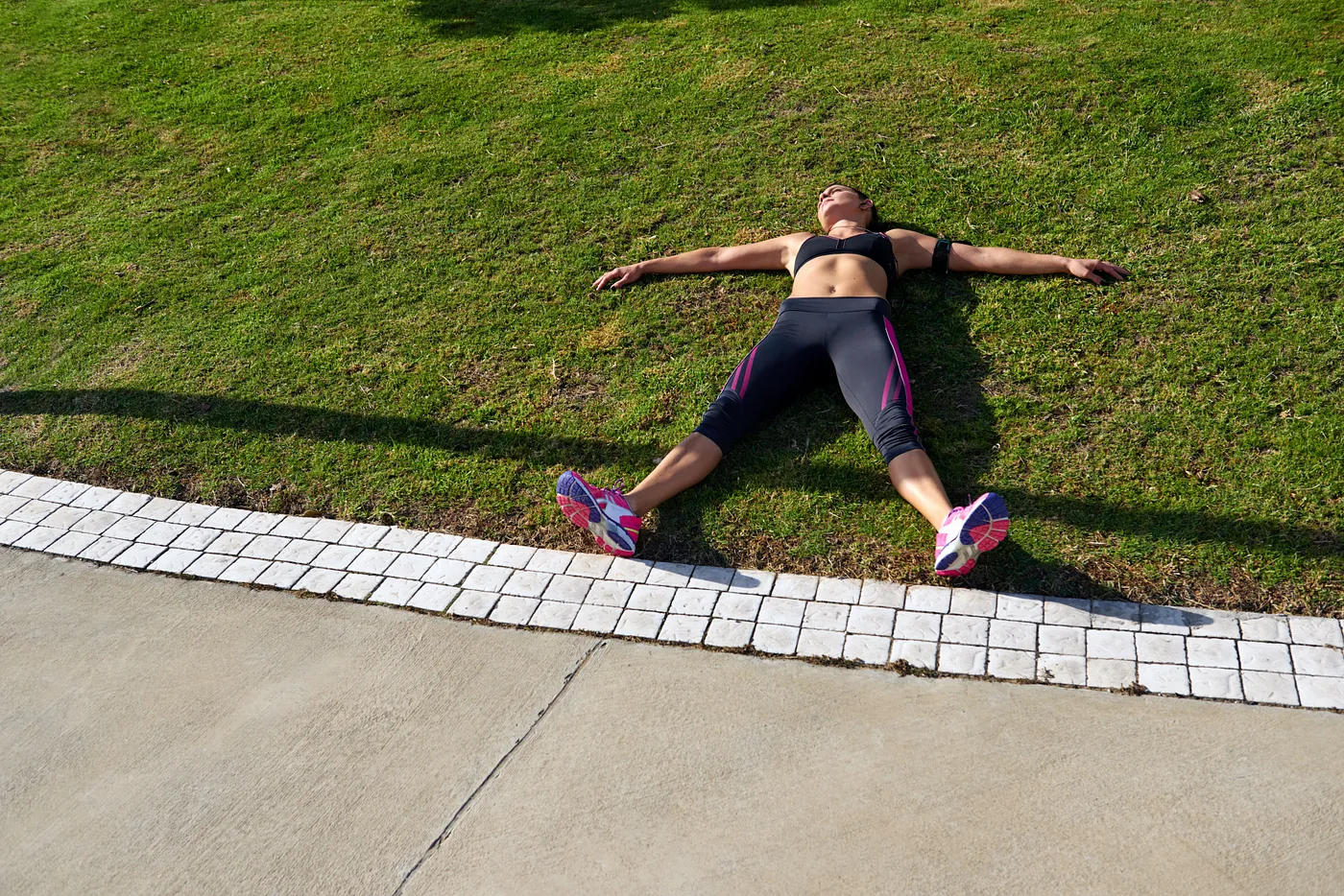An exhausted female athlete lying on the grass after running